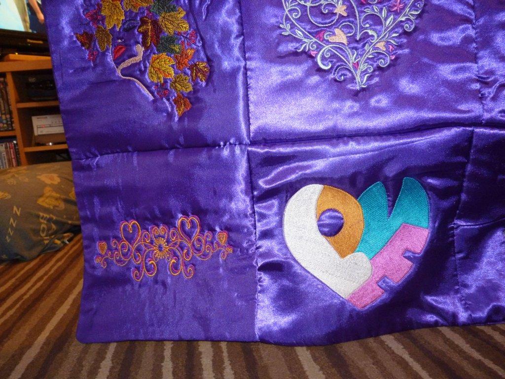 An embroidery design of colorful leaves, a decorative heart with swirls, and the word "LOVE" creatively placed within a heart shape.