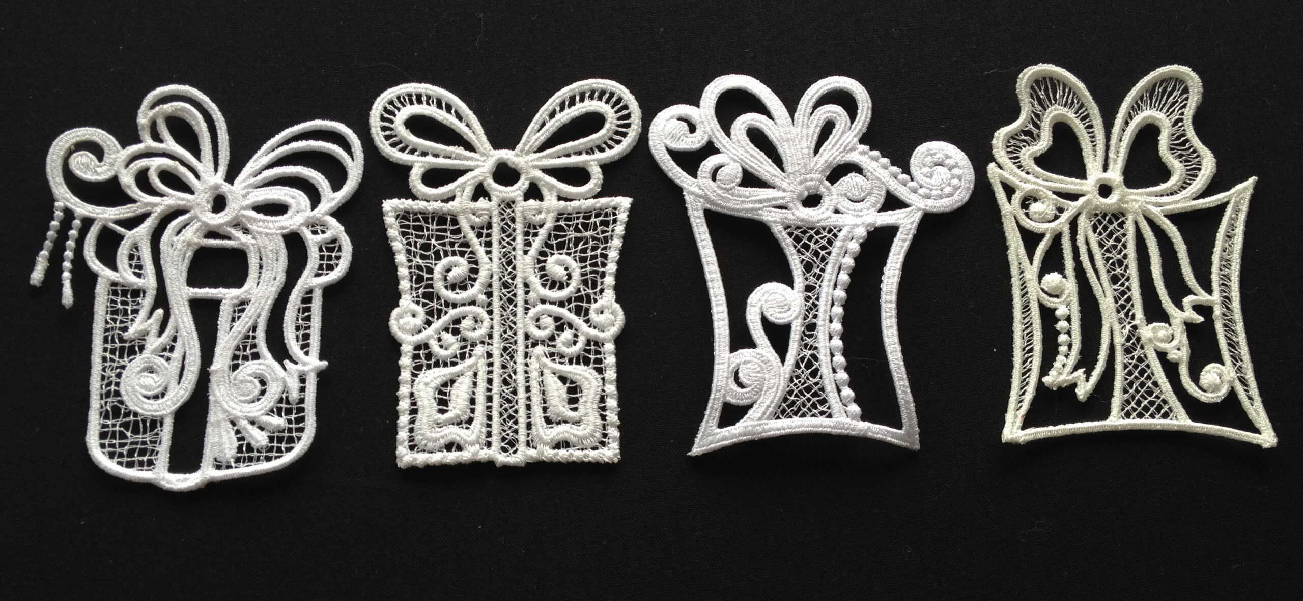 An embroidery design of four intricately crafted gift boxes adorned with bows and decorative patterns.