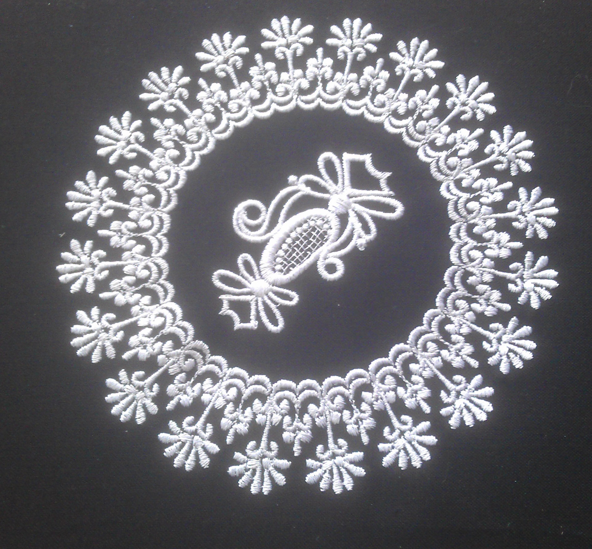 An embroidery design of a circular motif featuring intricate floral patterns surrounding a central decorative element.