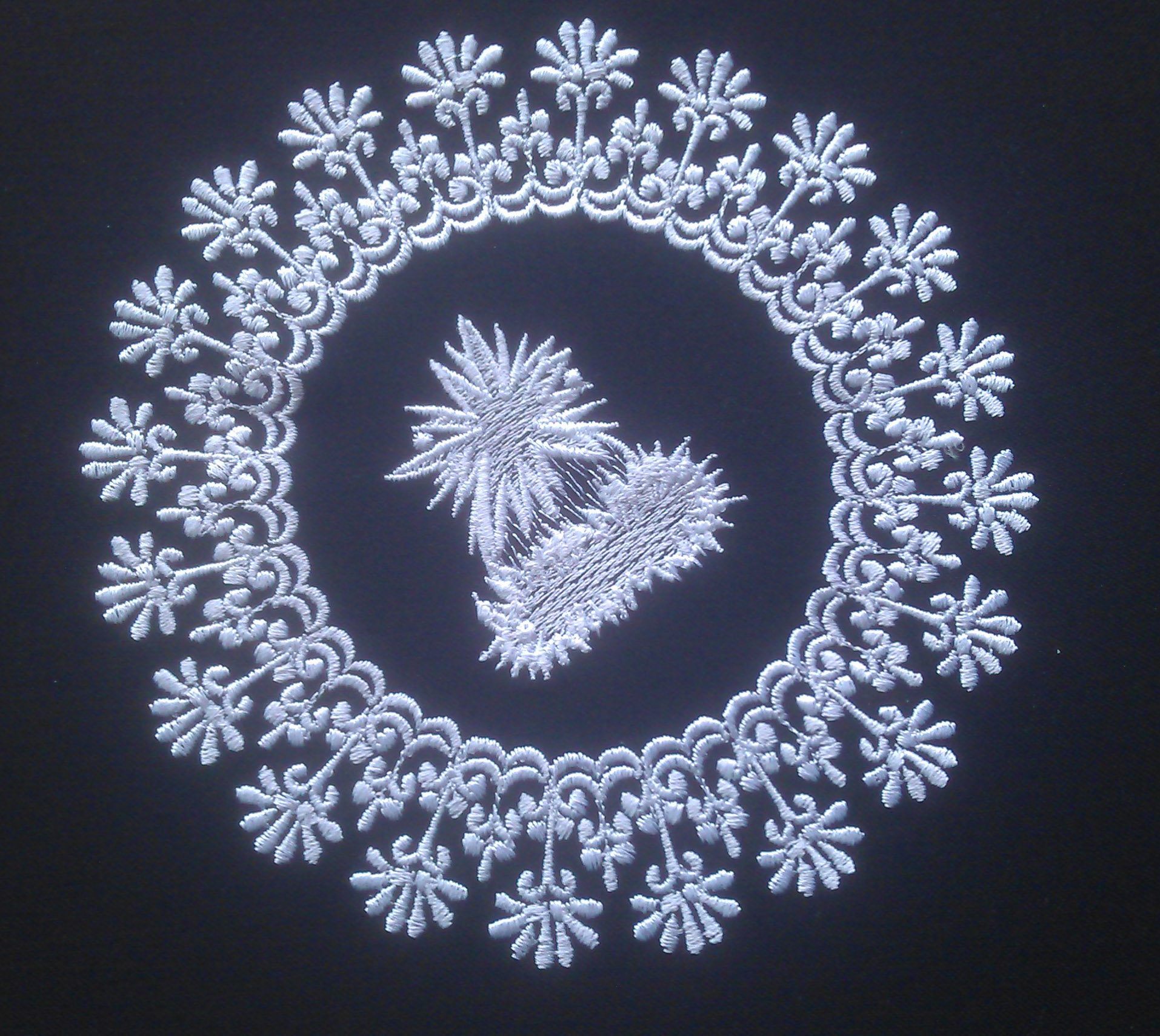 An embroidery design of a stylized floral motif surrounding a central decorative element.