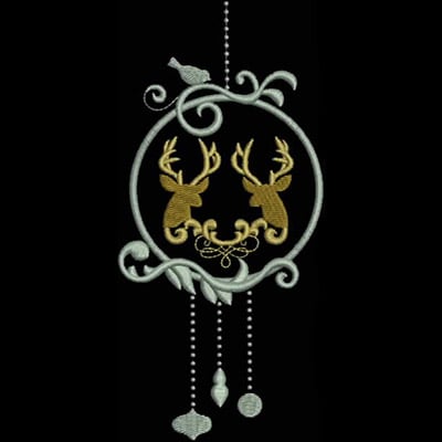 An embroidery design of two stylized deer heads framed within an ornate circular motif, adorned with decorative swirls and hanging elements.