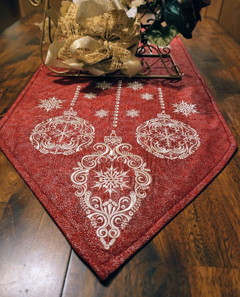 An embroidery design of elegant ornaments and snowflakes on a rich red background.