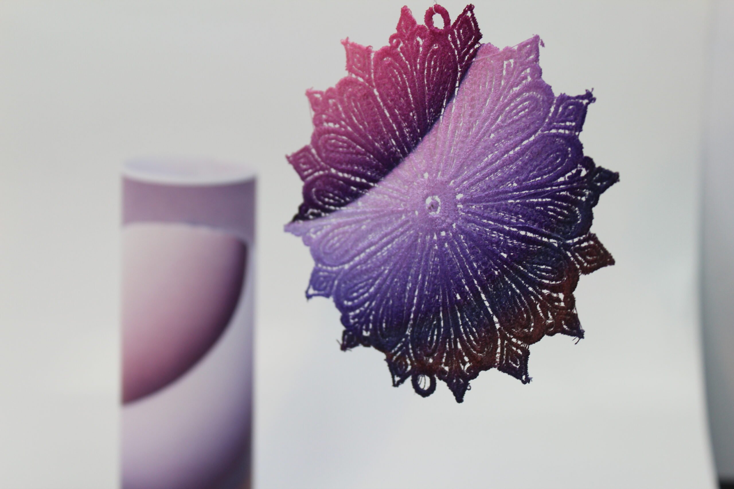 An embroidery design of a richly detailed, circular motif featuring a gradient of purple hues transitioning from deep violet to soft lavender.