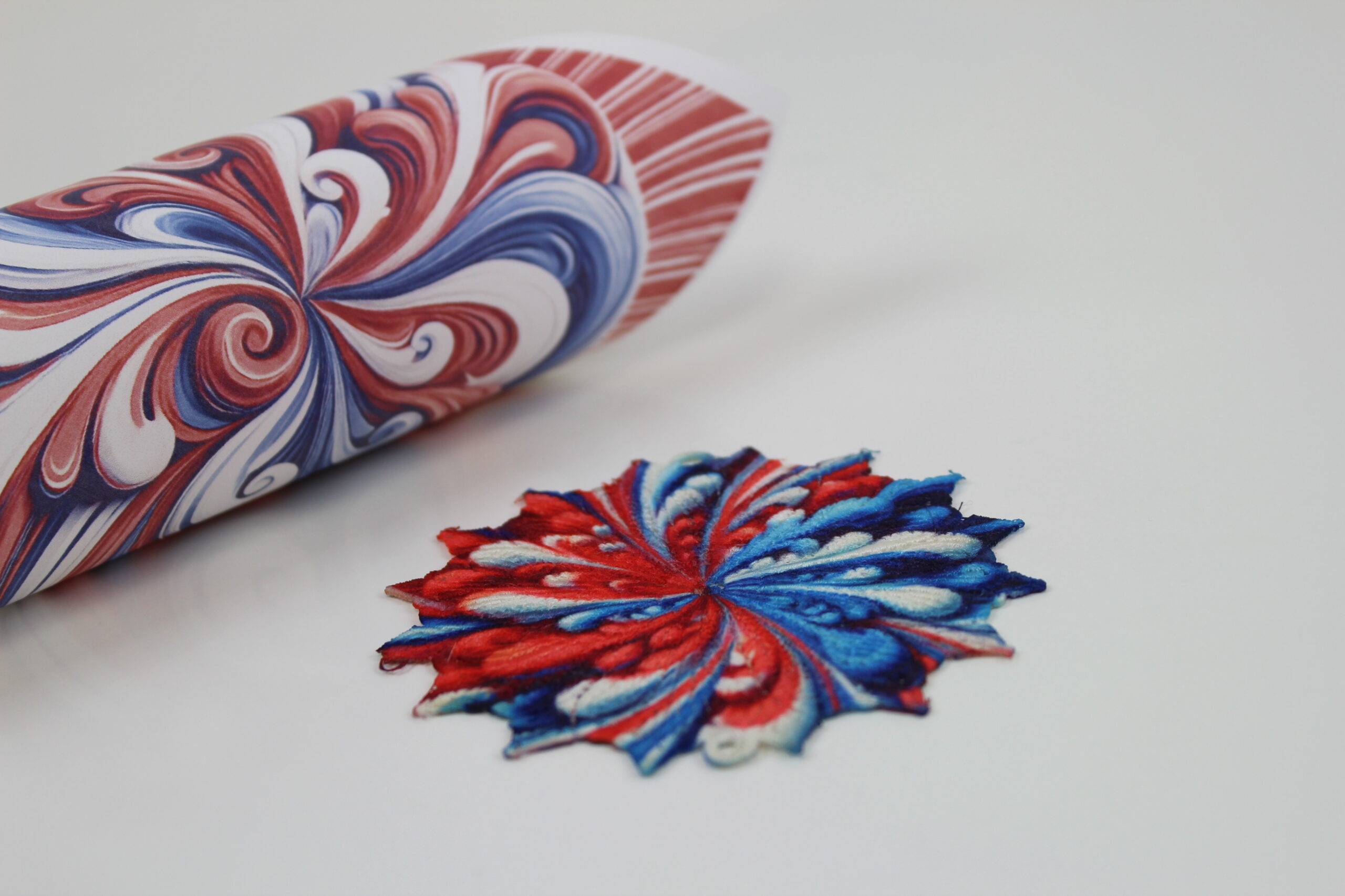 An embroidery design of a vibrant, symmetrical floral motif featuring deep reds and blues intertwined with white accents.