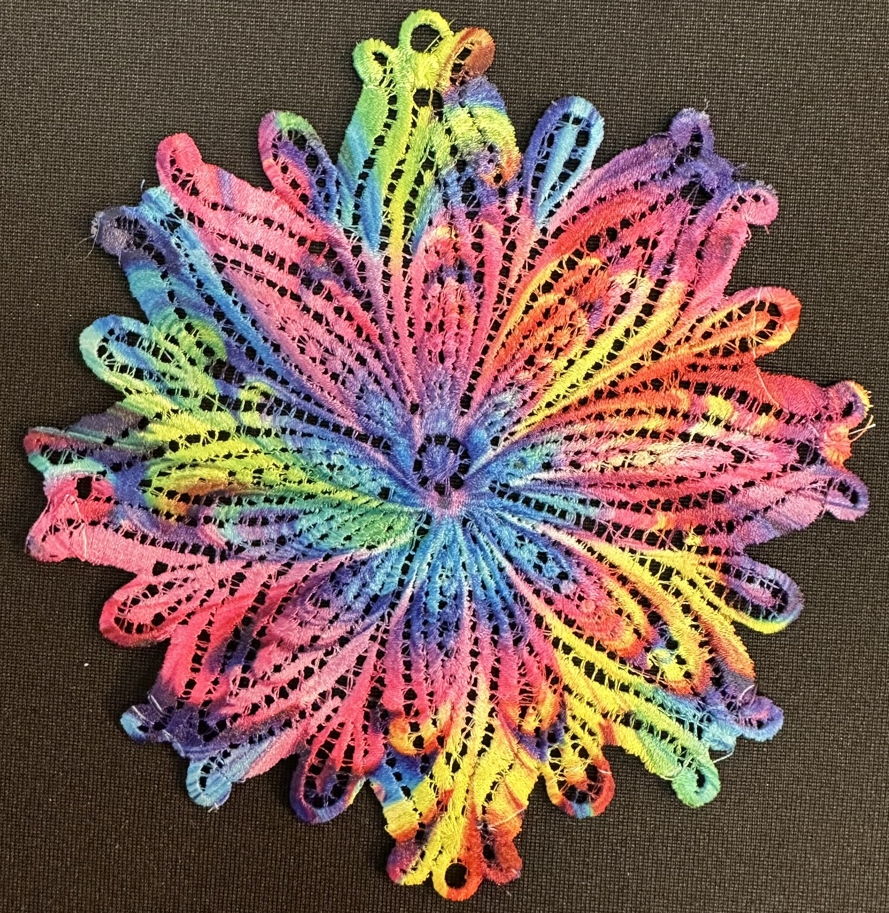 An embroidery design of a vibrant, multi-colored floral pattern featuring intricate loops and curves.