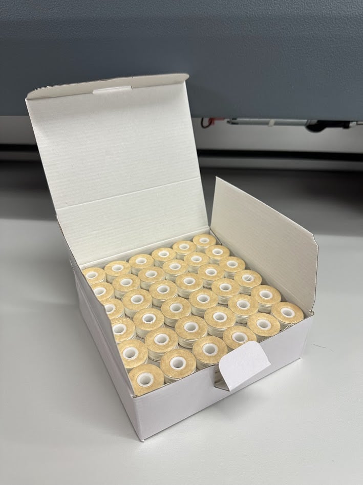 An embroidery design of a neatly arranged box containing multiple spools of thread.