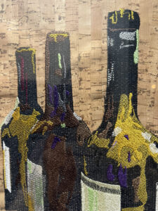 An embroidery design of three wine bottles featuring intricate details and vibrant colors.