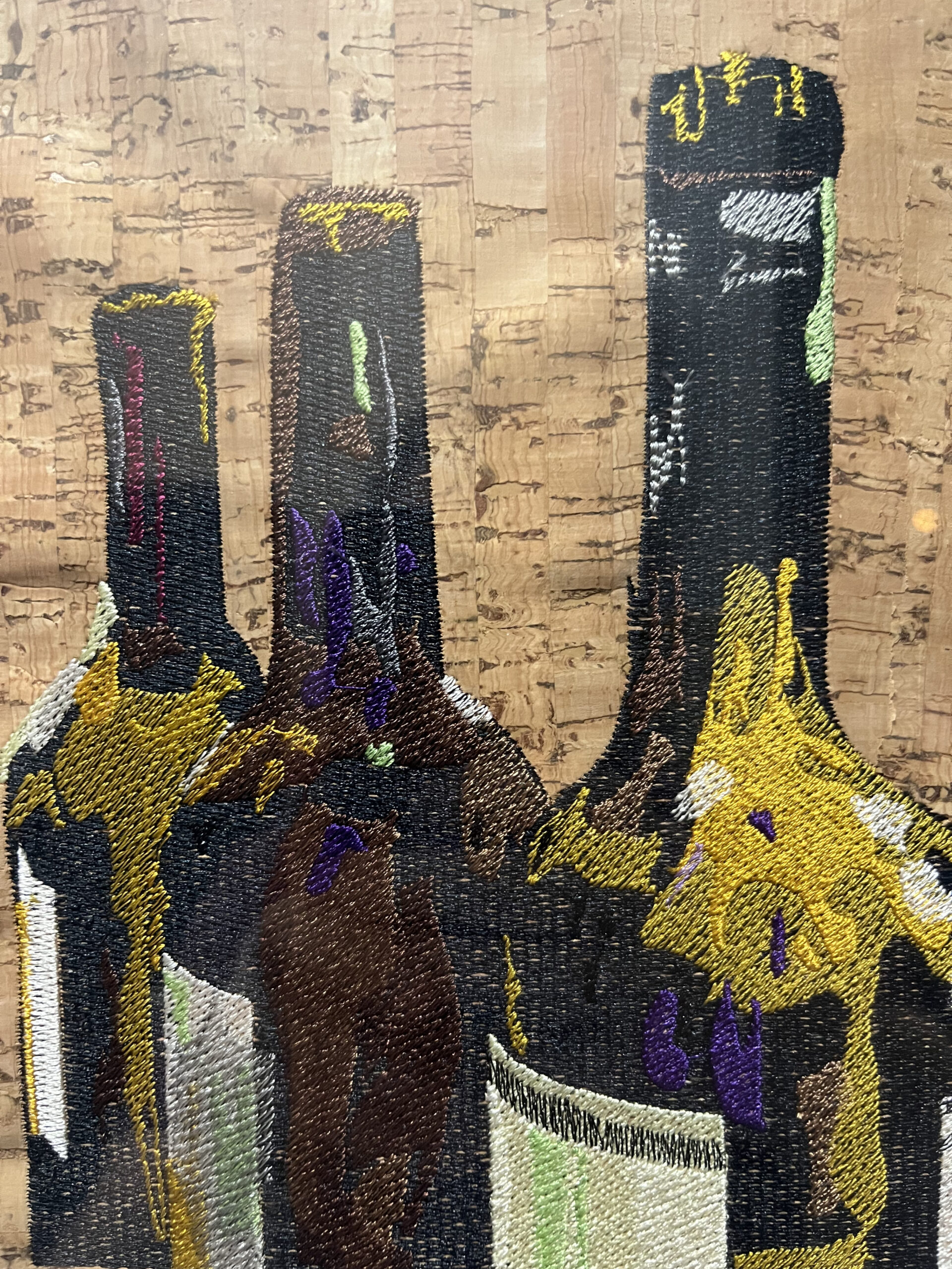 An embroidery design of three wine bottles featuring intricate details and vibrant colors.
